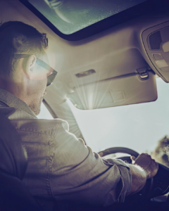 Man driving in a car with reduced visibility due to the sun glare